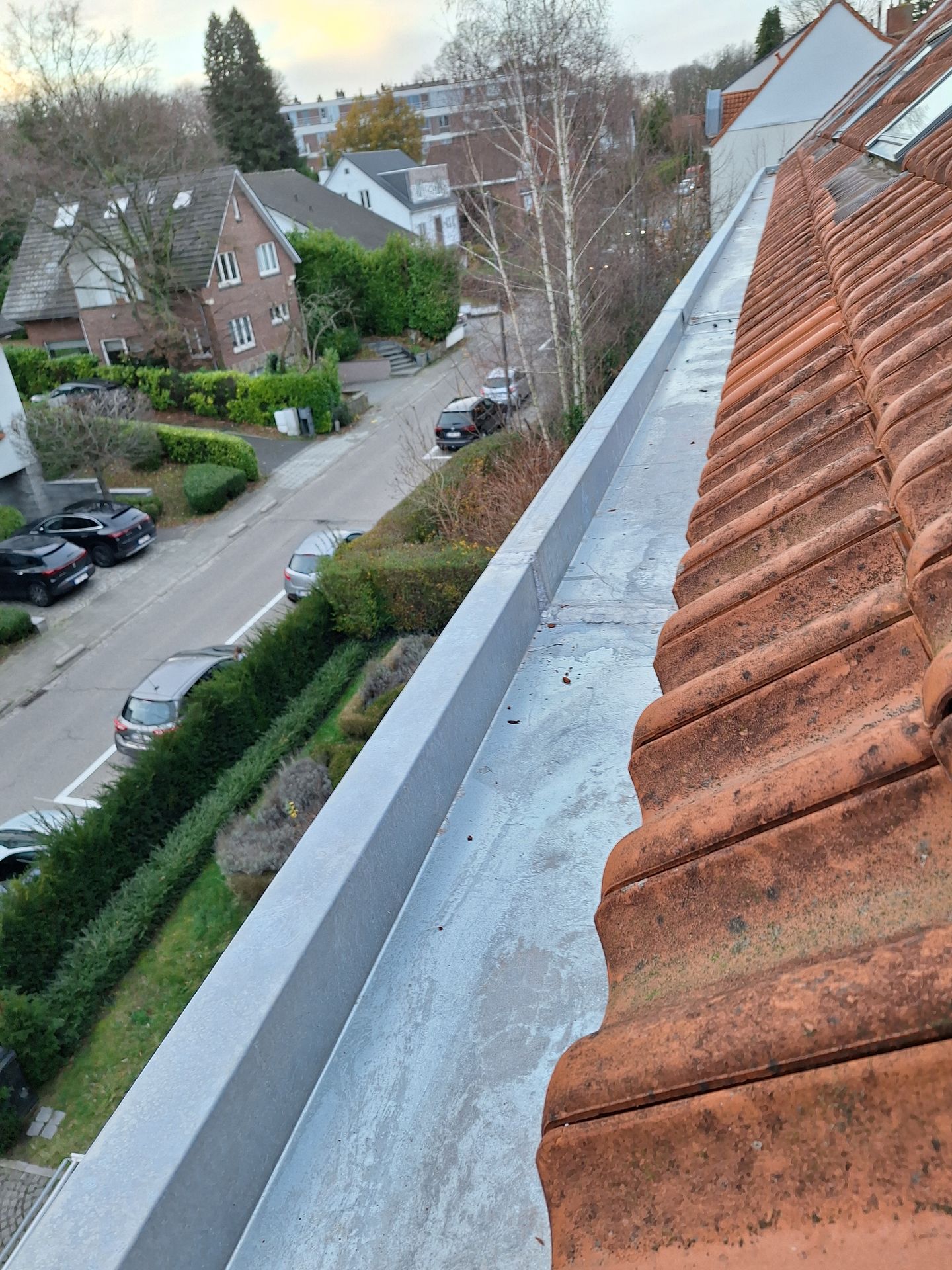 Installation d'un chéneau encaissé en zinc avec soudures étanches le long d'une toiture en tuiles terre cuite. Vue sur le système d'évacuation des eaux pluviales et la corniche métallique, garantissant la protection des façades contre l'humidité en milieu résidentiel.